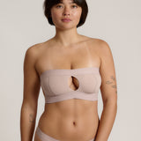 Woman wearing a beige strapless against a plain background