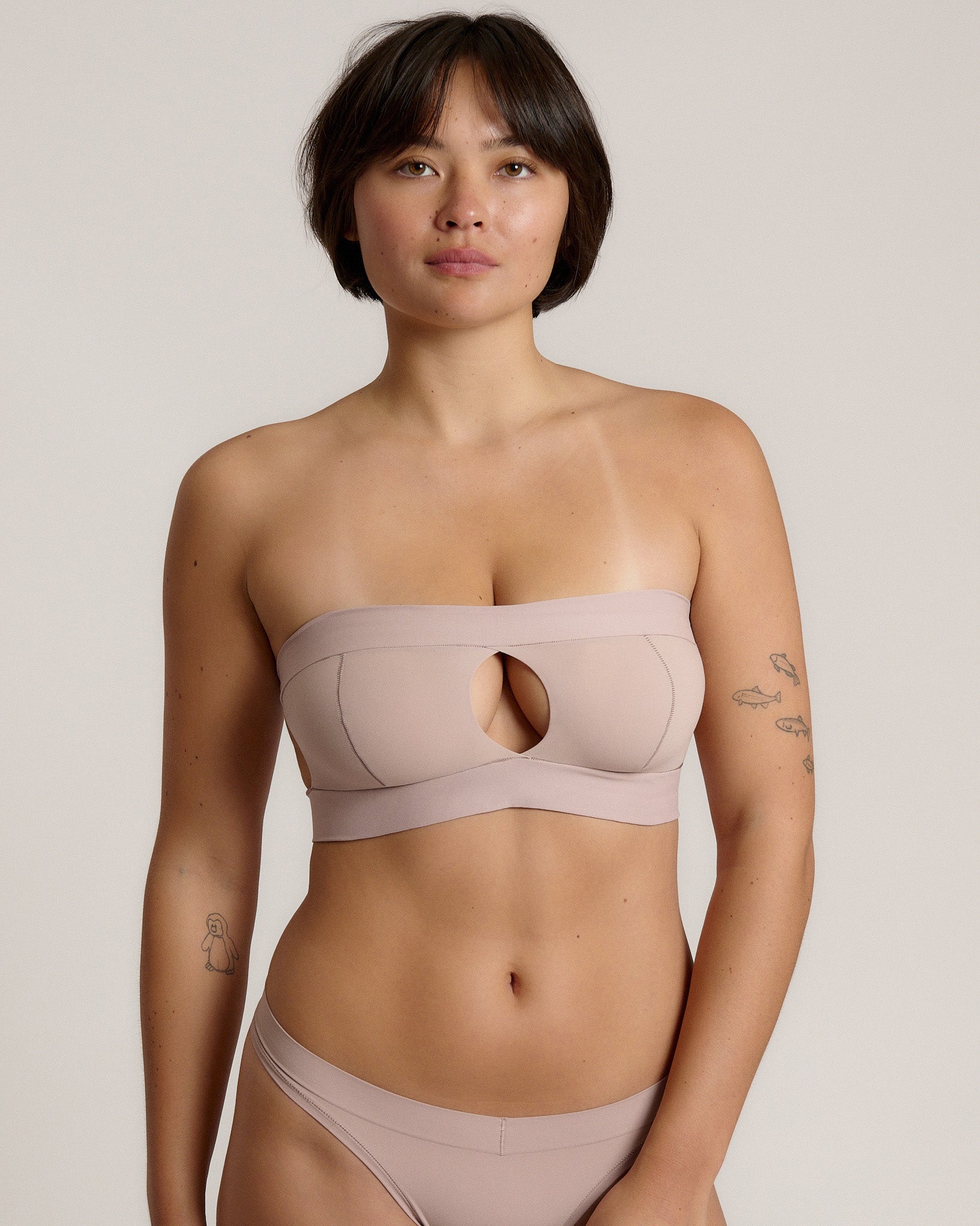 Woman wearing a beige strapless against a plain background