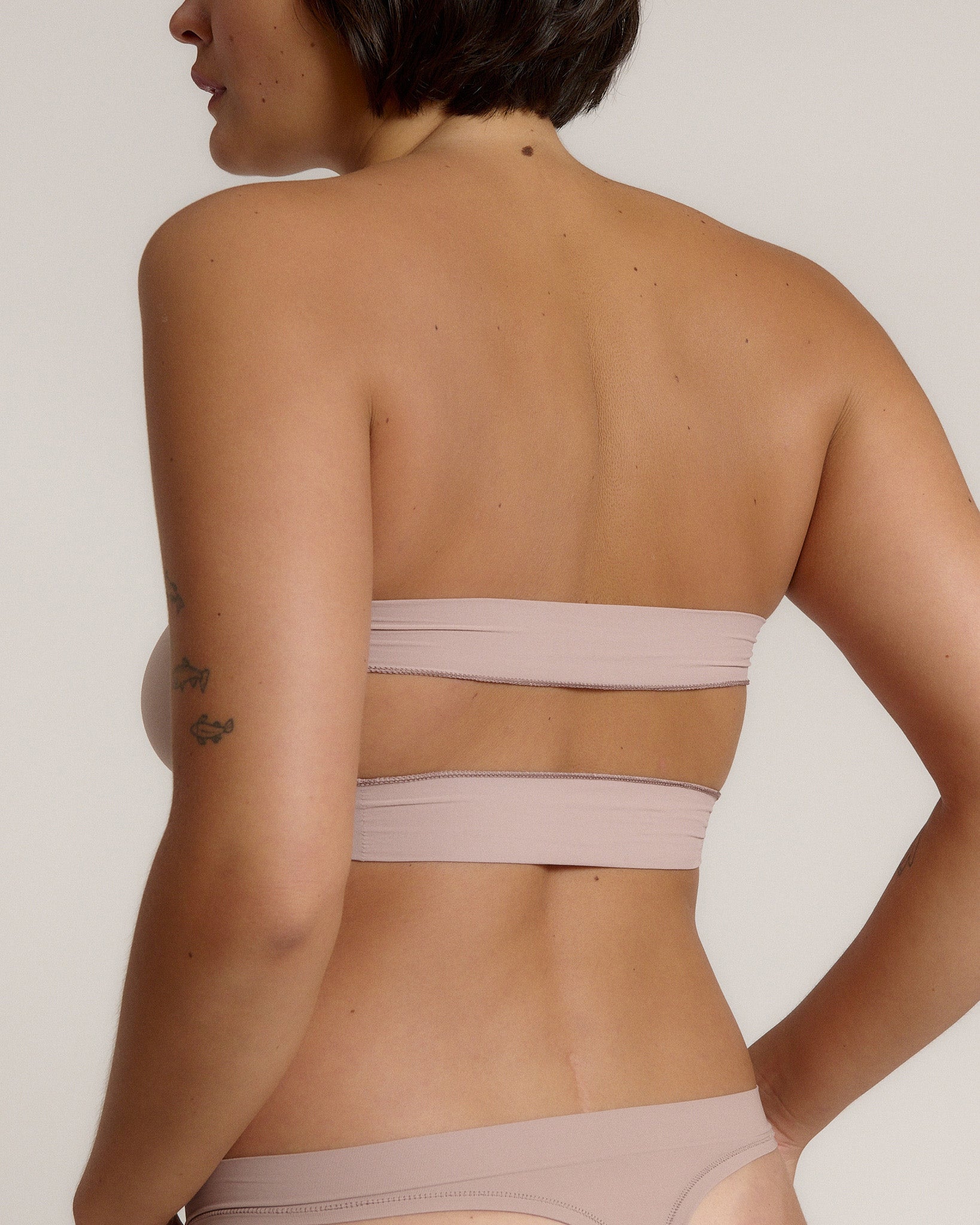 Woman wearing a beige strapless against a plain background