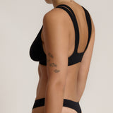 Woman wearing black tee system on plain background