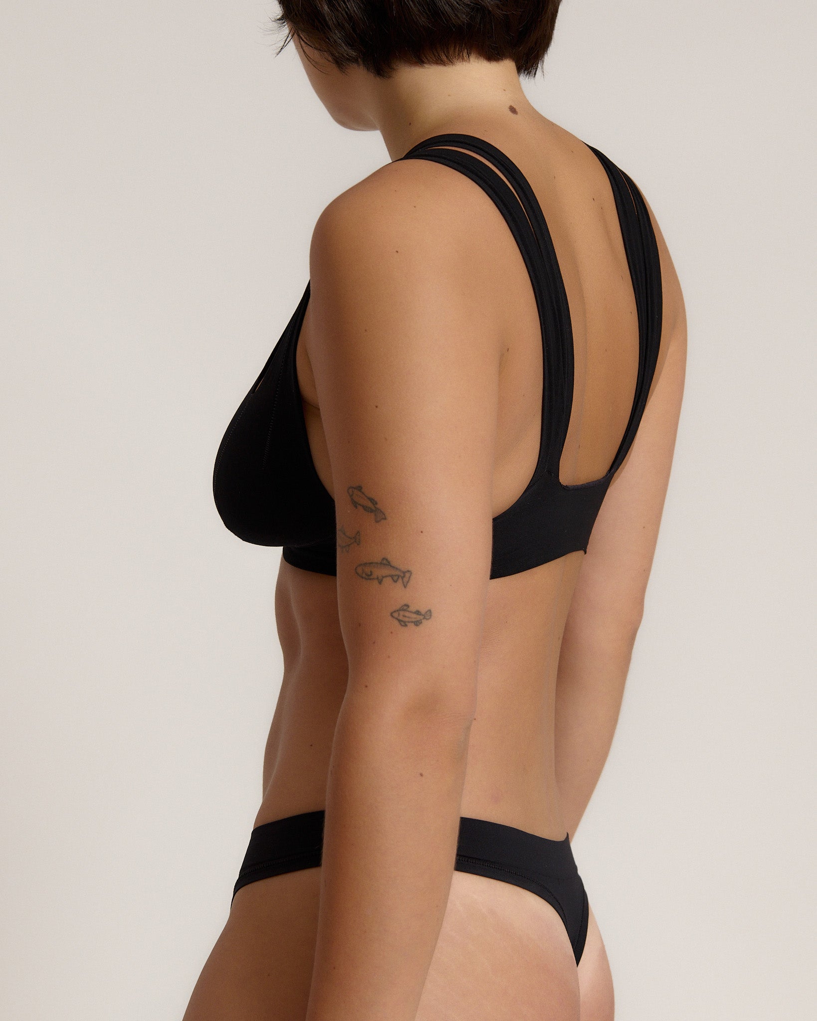 Woman wearing black tee system on plain background