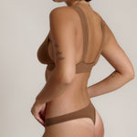 Woman wearing a brown bra against a neutral background