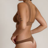 Woman wearing a brown bra against a neutral background