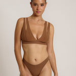 Woman wearing a brown bra against a neutral background