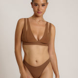 Woman wearing a brown bra against a neutral background