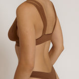 Woman wearing a brown bra against a neutral background