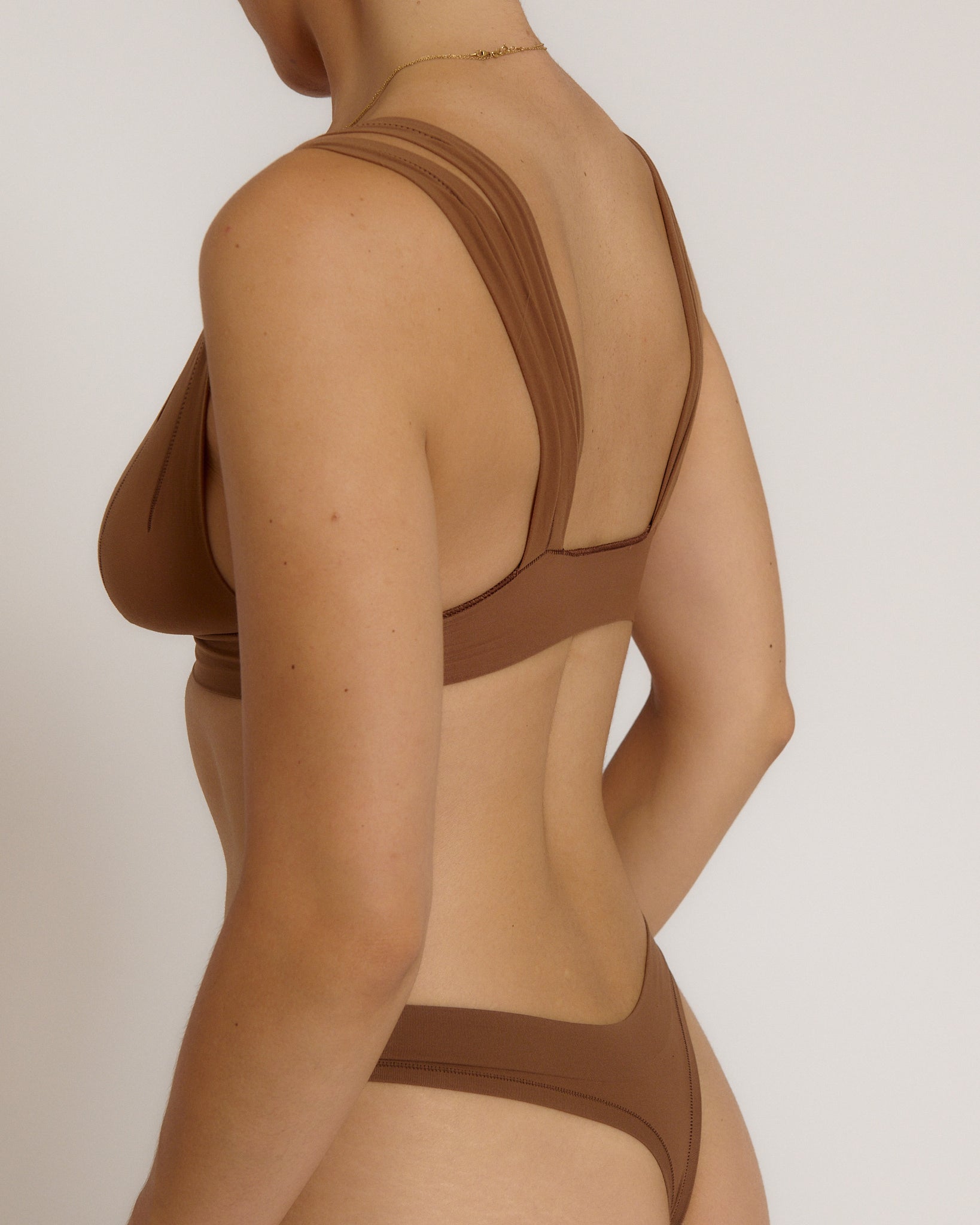 Woman wearing a brown bra against a neutral background