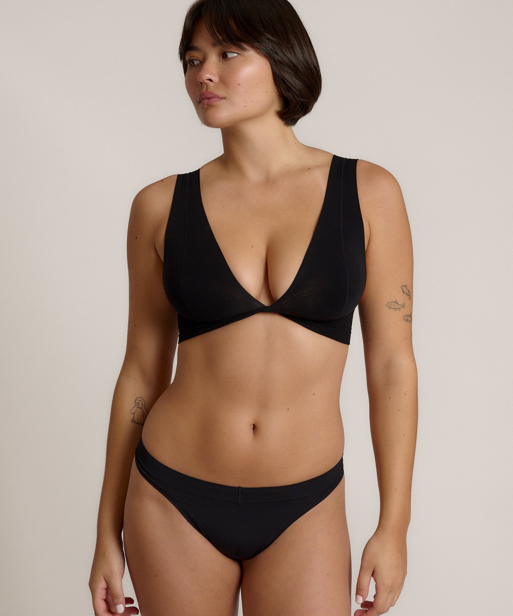 Woman wearing a black twist system and thong against a plain background