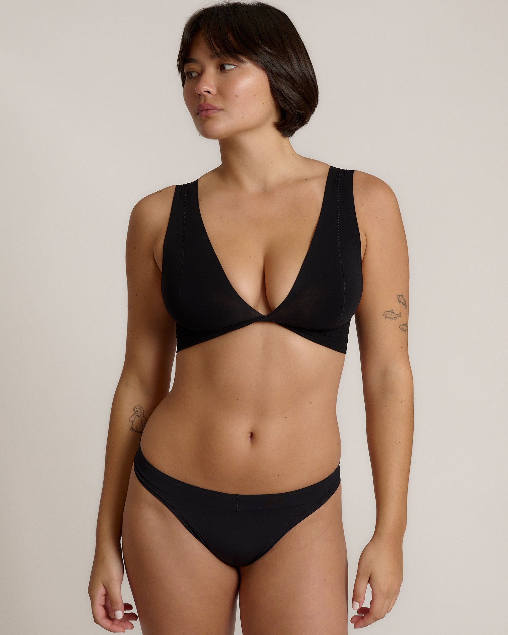 Woman wearing a black twist system and thong against a plain background