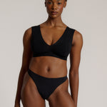 A woman wearing a black vii system with wide straps and a deep neckline.