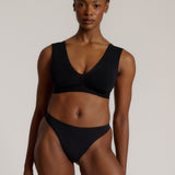A woman wearing a black vii system with wide straps and a deep neckline.
