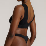 A woman wearing a black vii system with wide straps and a deep neckline.