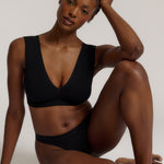 A woman wearing a black vii system with wide straps and a deep neckline.