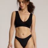 A woman wearing a black vii system with wide straps and a deep neckline.