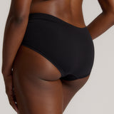 Person wearing black high-waisted underwear on a plain background
