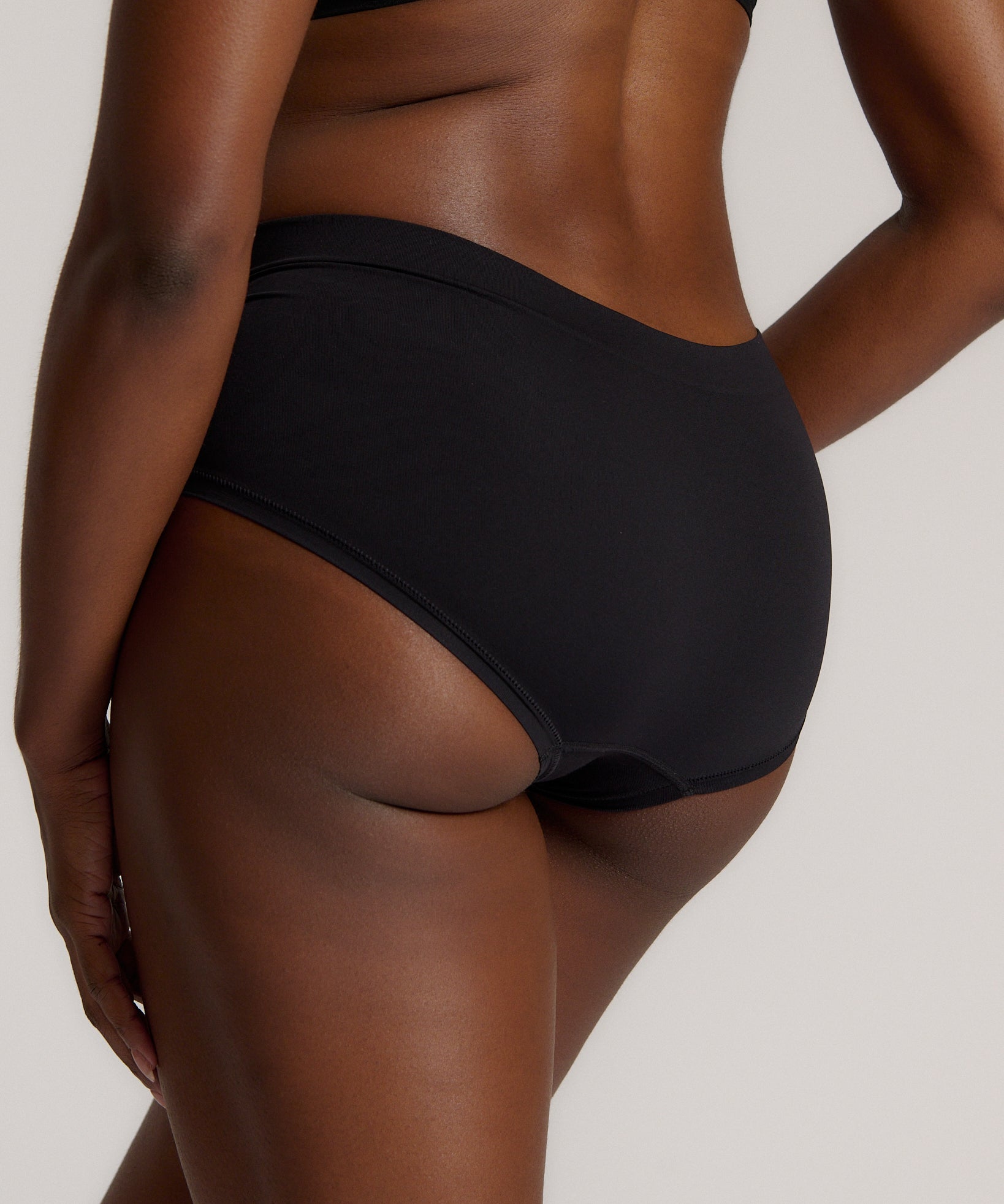 Person wearing black high-waisted underwear on a plain background