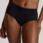 Person wearing black high-waisted underwear on a plain background
