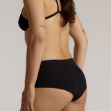 Person wearing black high-waisted underwear on a plain background