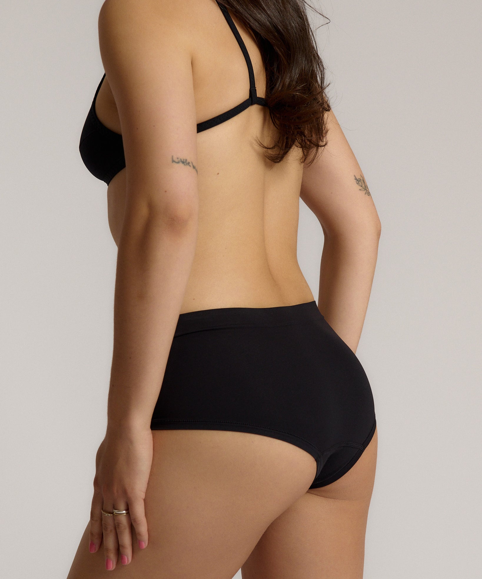 Person wearing black high-waisted underwear on a plain background