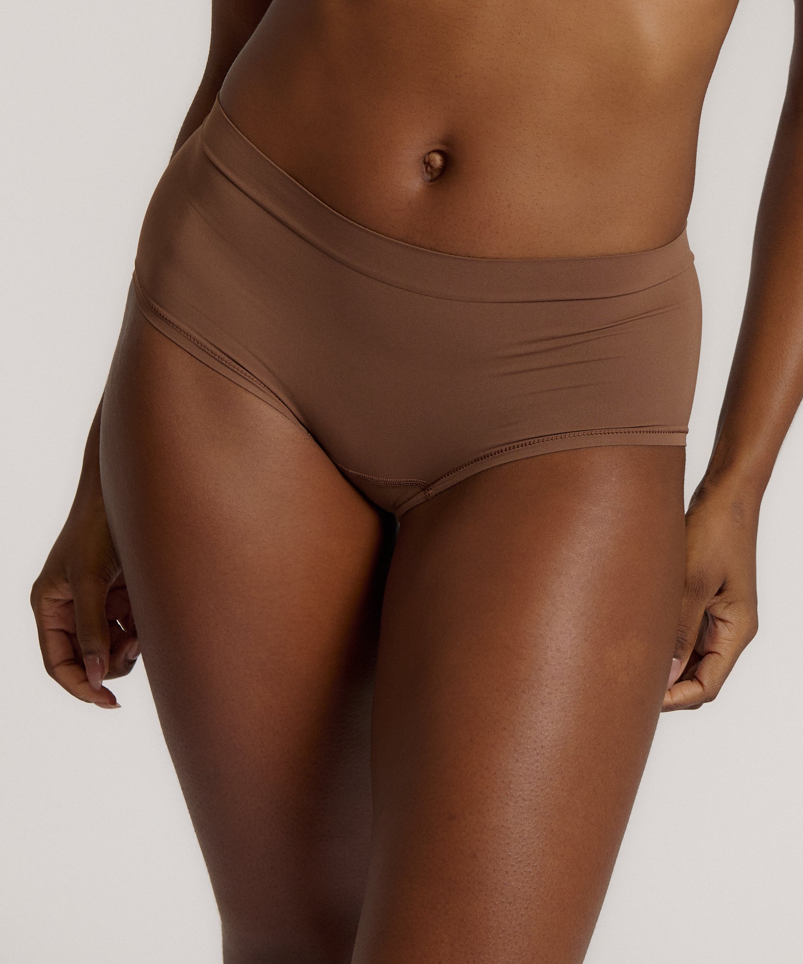 A mid-rise brown brief underwear with a seamless design, showing the waistband and part of the leg openings.