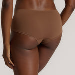 A mid-rise brown brief underwear with a seamless design, showing the waistband and part of the leg openings.
