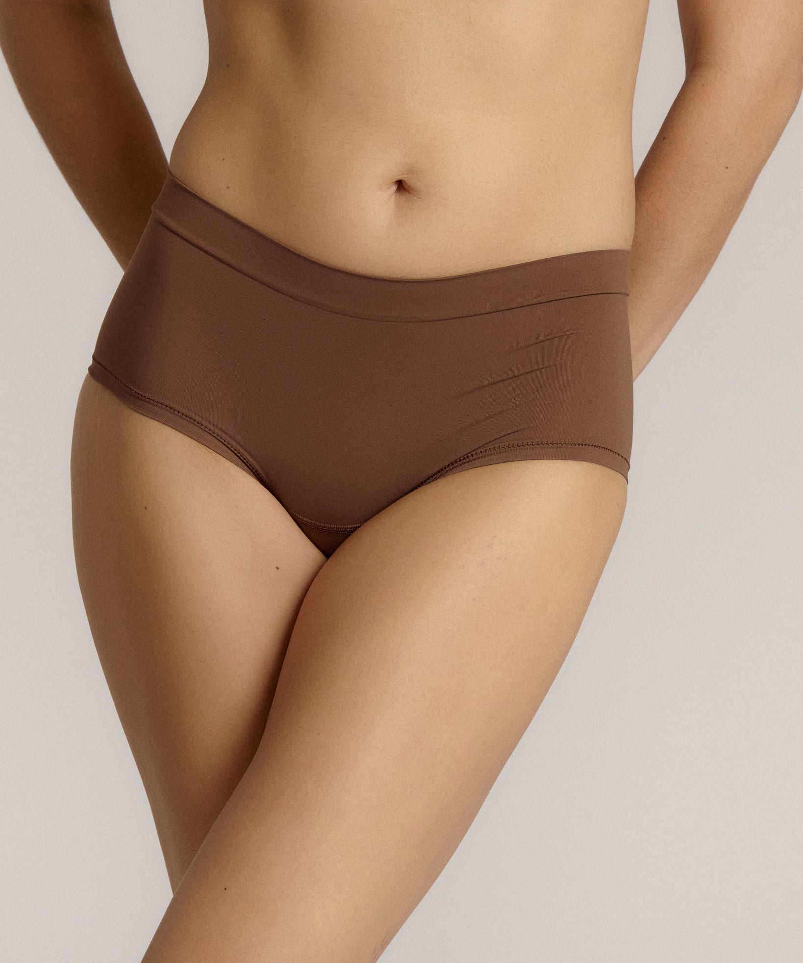 A mid-rise brown brief underwear with a seamless design, showing the waistband and part of the leg openings.