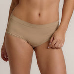 A person wearing a beige mid-rise brief with no visible lines, made from a stretchy fabric, showcasing the design's comfort and fit.