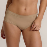 A person wearing a beige mid-rise brief with no visible lines, made from a stretchy fabric, showcasing the design's comfort and fit.