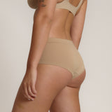 A person wearing a beige mid-rise brief with no visible lines, made from a stretchy fabric, showcasing the design's comfort and fit.