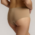 A person wearing a beige mid-rise brief with no visible lines, made from a stretchy fabric, showcasing the design's comfort and fit.