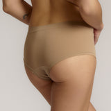 A person wearing a beige mid-rise brief with no visible lines, made from a stretchy fabric, showcasing the design's comfort and fit.