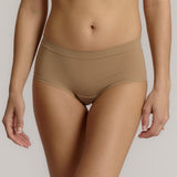 A person wearing a beige mid-rise brief with no visible lines, made from a stretchy fabric, showcasing the design's comfort and fit.