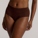 A person wearing a brown mid-rise brief underwear, showing the side profile of the underwear with no visible lines.