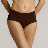 A person wearing a brown mid-rise brief underwear, showing the side profile of the underwear with no visible lines.