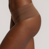 A person wearing a pair of brown, mid-rise women's underwear.
