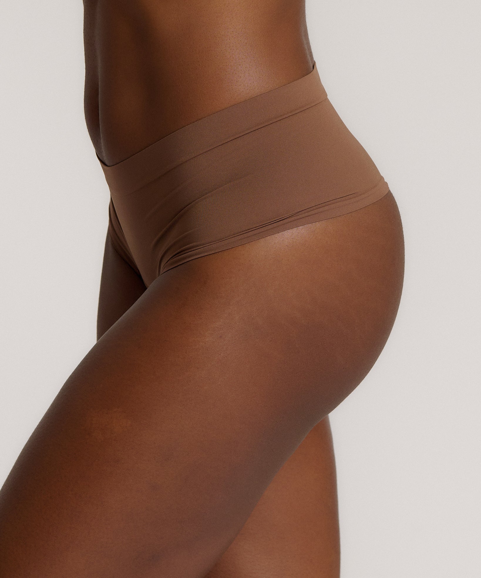 A person wearing a pair of brown, mid-rise women's underwear.
