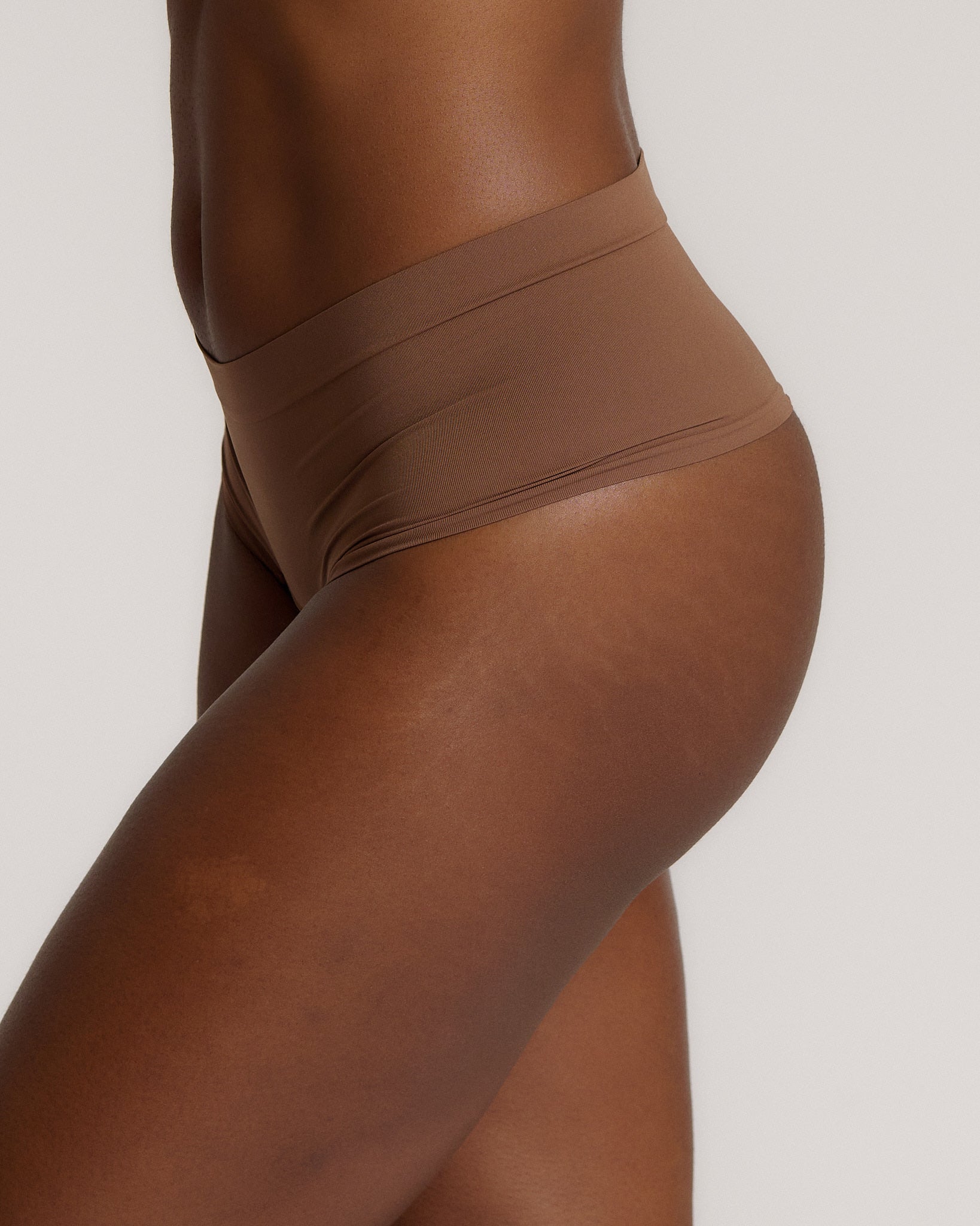 A person wearing a pair of brown, mid-rise women's underwear.