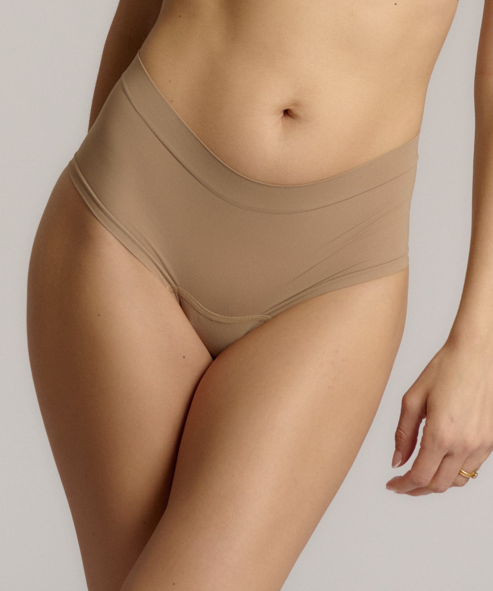A pair of beige, mid-rise women's underwear.