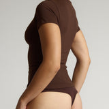 Person wearing a brown t-shirt against a plain background