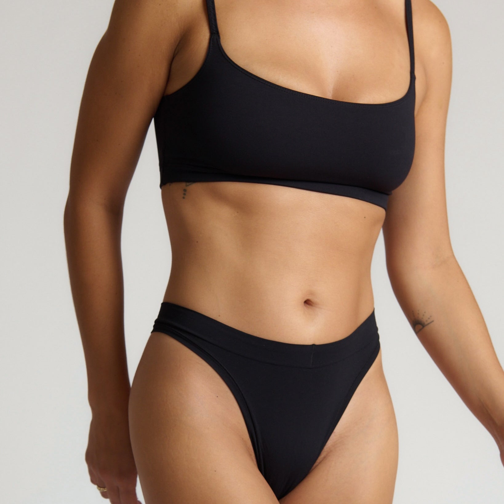 Person wearing a black bra set on a neutral background