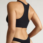 woman wearing black racerback on plain background