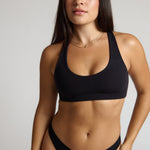 woman wearing black racerback on plain background