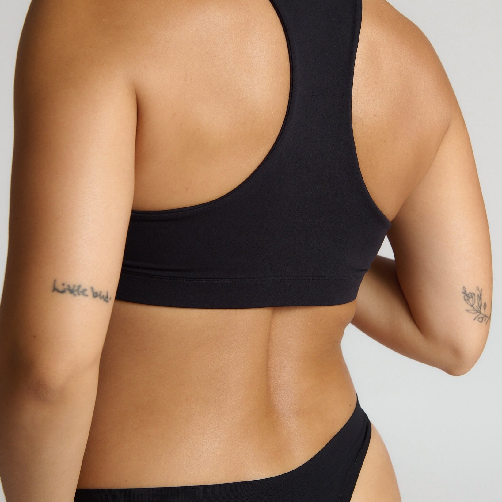 woman wearing black racerback on plain background