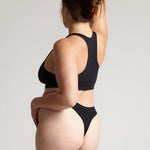 woman wearing black racerback on plain background