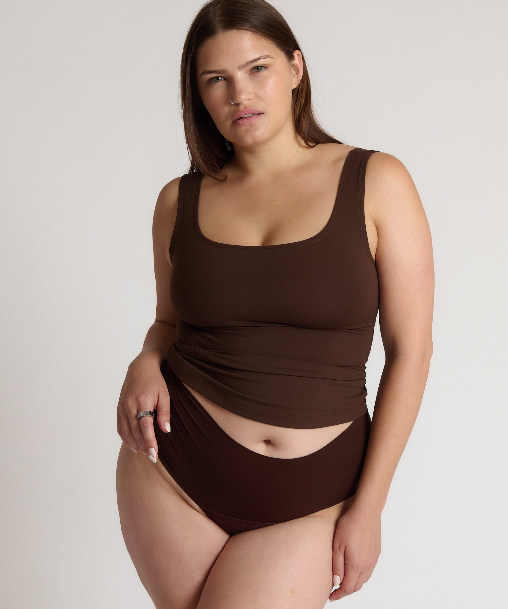 Woman wearing a brown tank top against a plain background