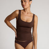 Woman wearing a brown tank top against a plain background