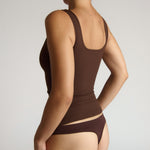 Woman wearing a brown tank top against a plain background