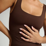 Woman wearing a brown tank top against a white background
