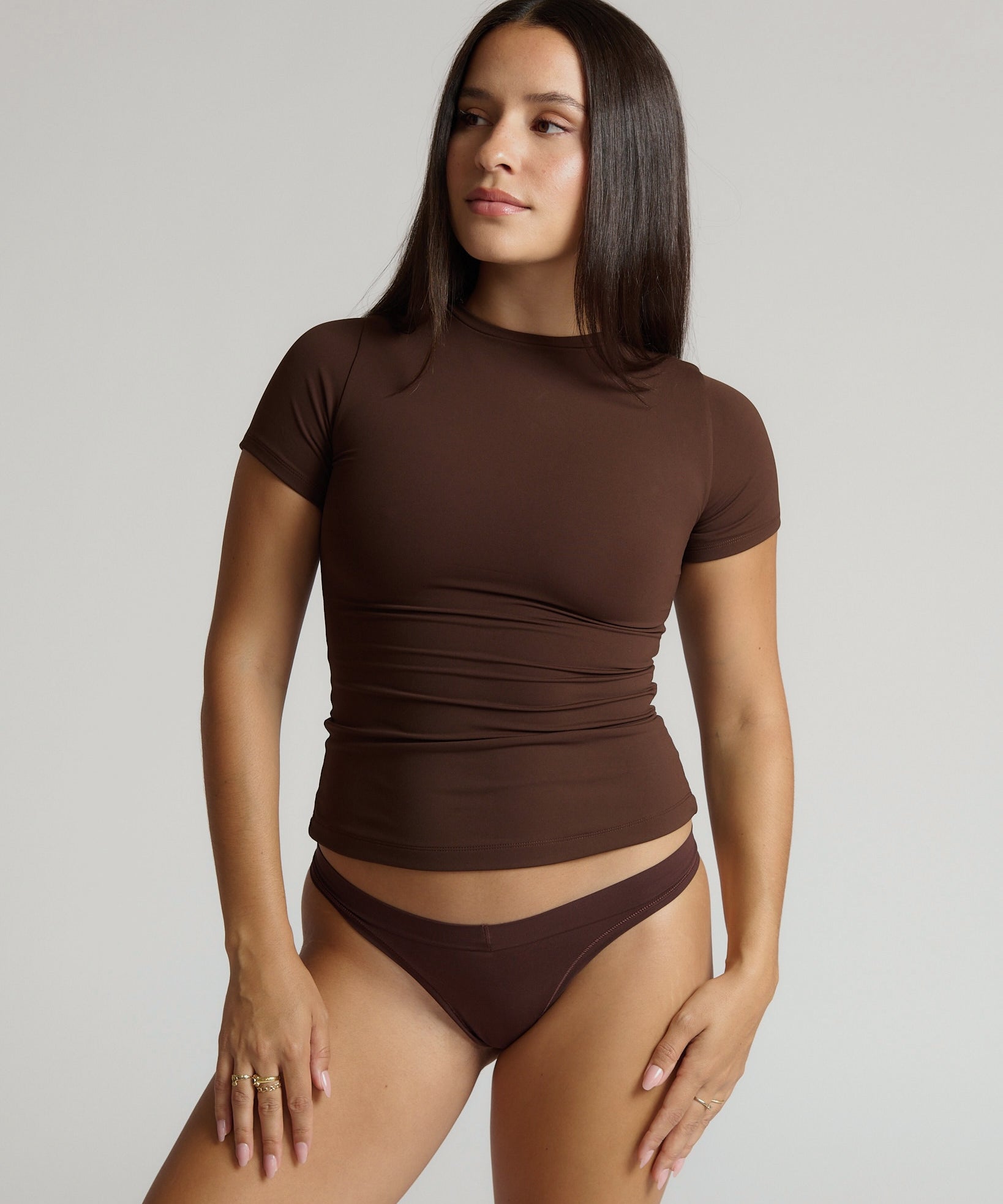 Woman wearing a brown short-sleeve top and underwear set against a plain background