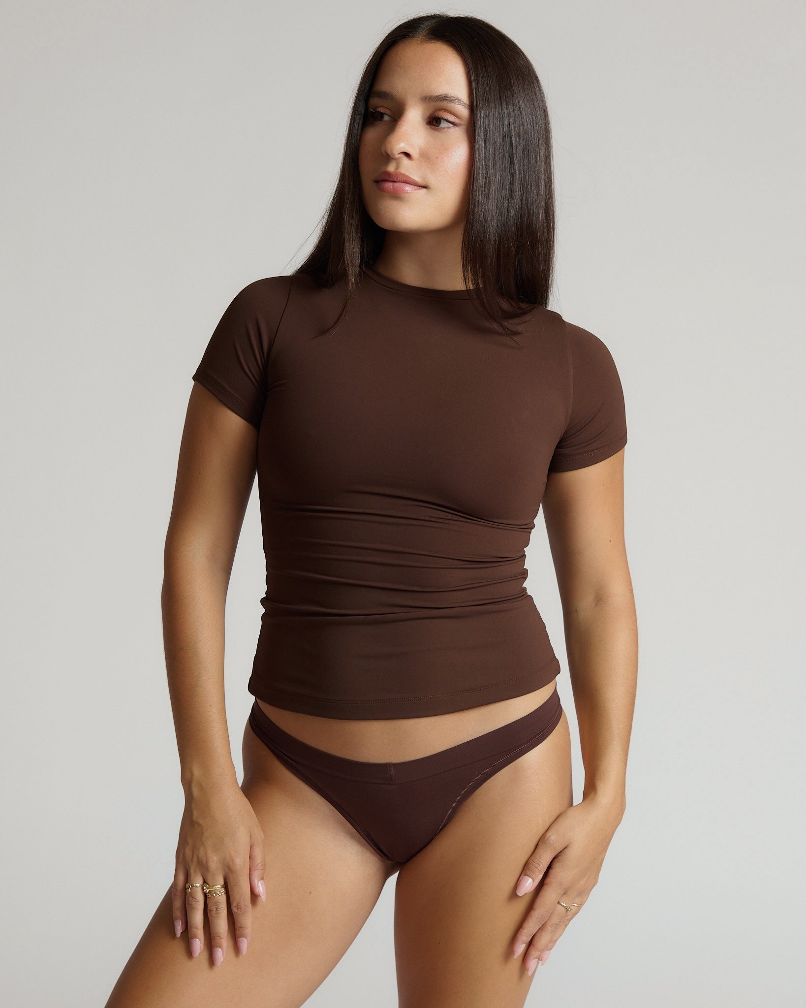 Woman wearing a brown short-sleeve top and underwear set against a plain background